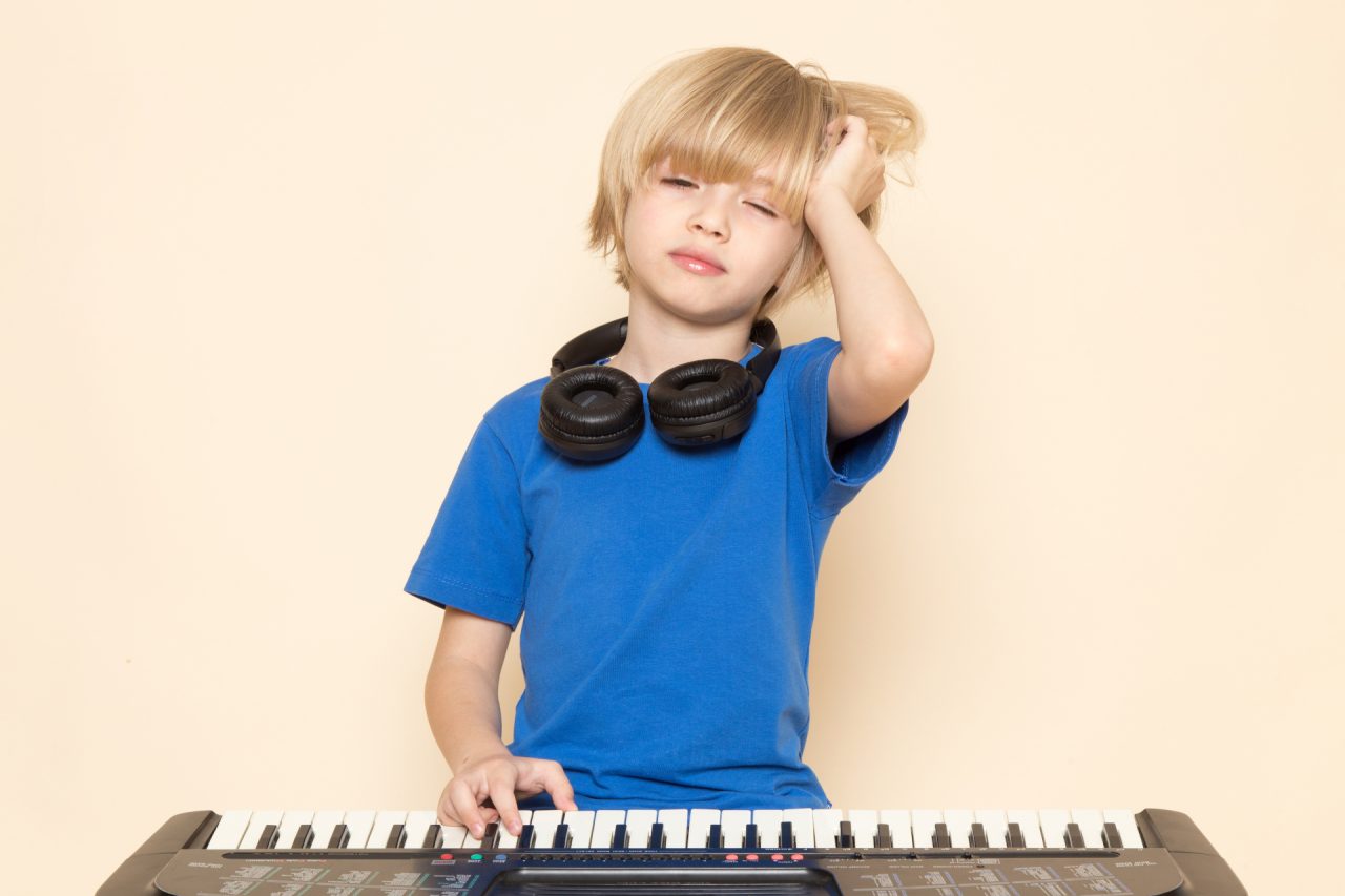 front-view-cute-little-boy-blue-t-shirt-with-black-headphones-playing-little-cute-piano-wanting-sleep